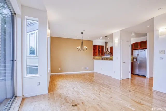 a view of a livingroom with wooden floor and kitchen space