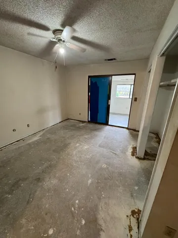 an empty room with windows and fan