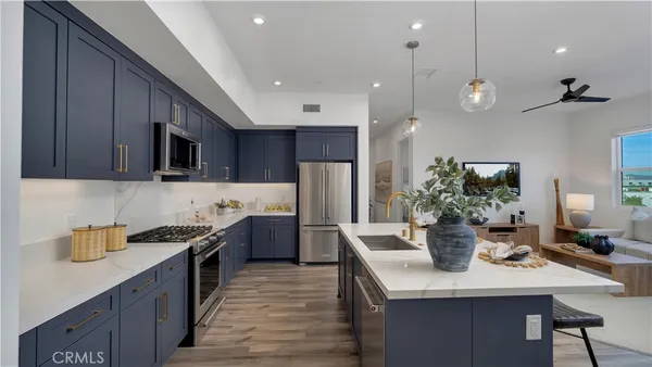 a kitchen with stainless steel appliances kitchen island granite countertop a refrigerator a sink dishwasher a stove and a dining table with wooden floor