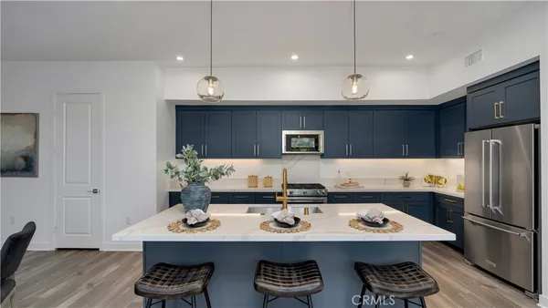 a kitchen with stainless steel appliances kitchen island granite countertop a sink a stove and refrigerator