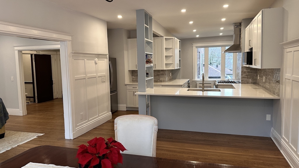 1521 Beacon Street, Unit 1 Brookline, MA 02446 - Photo 8 of 15 a kitchen with kitchen island granite countertop wooden cabinets and refrigerator