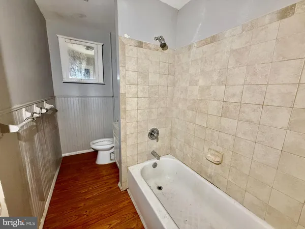 a bathroom with a tub a sink and wooden floor