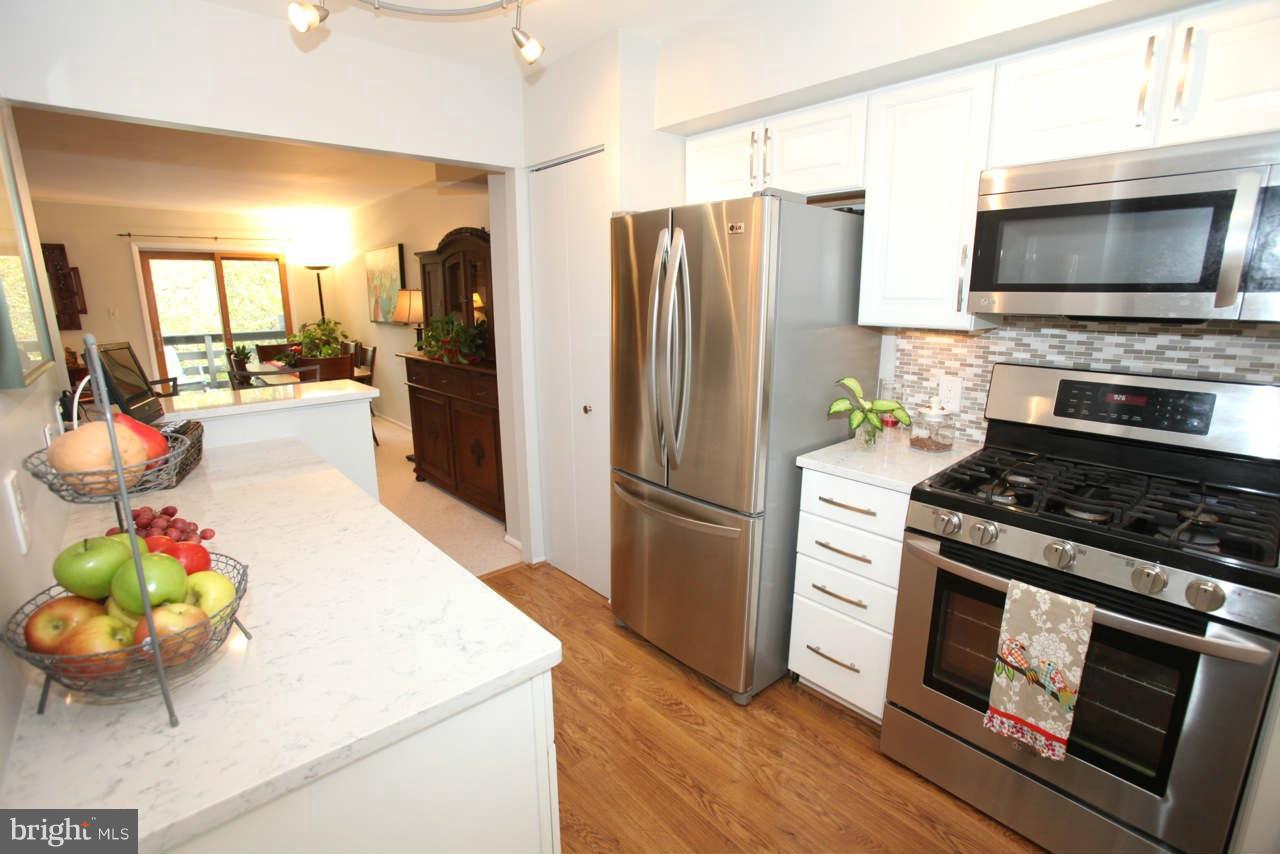 14 Stone Ridge Court, Unit 25 Baltimore, MD 21239 - Photo 1 of 30 a kitchen with stainless steel appliances kitchen island granite countertop a stove refrigerator and a fireplace with wooden floor