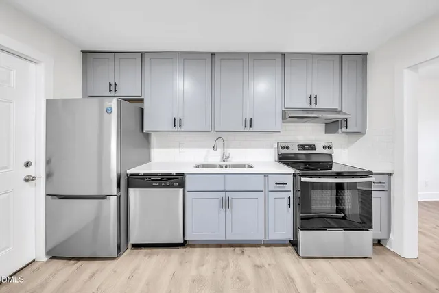 a kitchen with stainless steel appliances granite countertop a stove a refrigerator and a sink with wooden cabinets