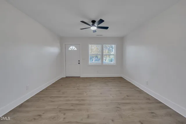 an empty room with windows and ceiling fan