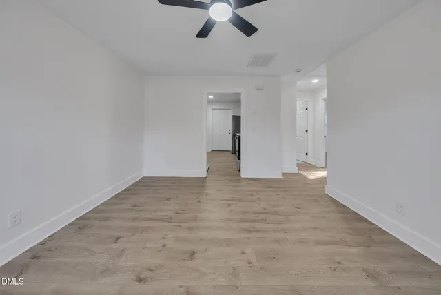an empty room with chandelier fan and windows