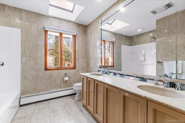 a bathroom with a granite countertop sink a toilet a mirror and shower