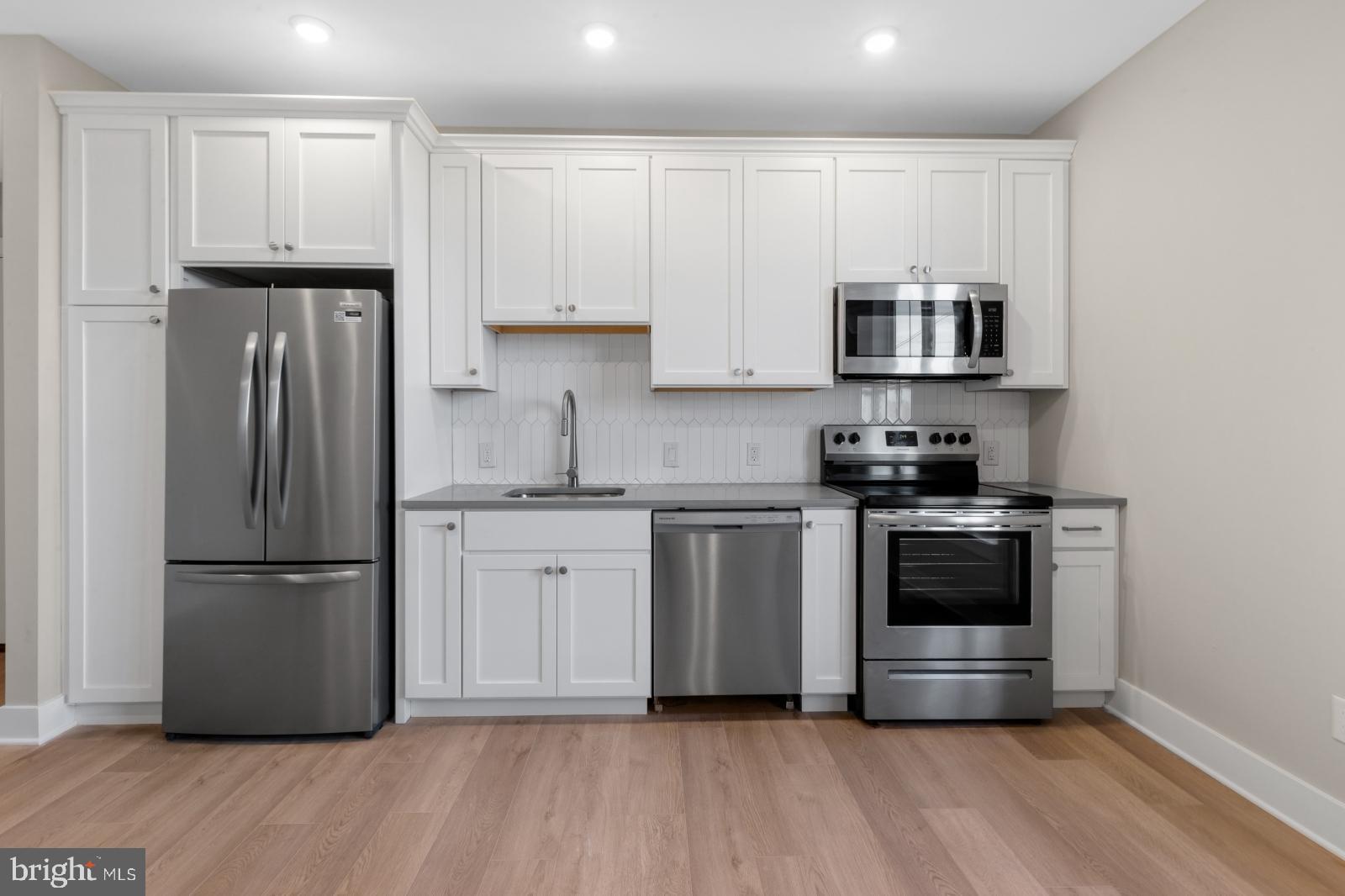 6712 Ridge Avenue, Unit 204 Philadelphia, PA 19128 - Photo 8 of 18 a kitchen with stainless steel appliances granite countertop a refrigerator stove a sink and white cabinets