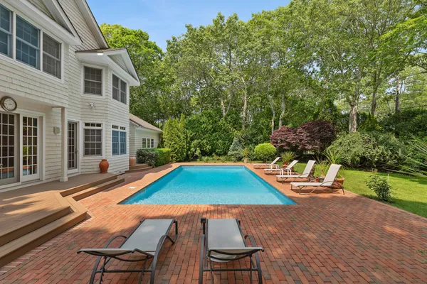 a view of backyard with swimming pool and seating space