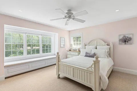 a bedroom with a bed and a large window with a chandelier