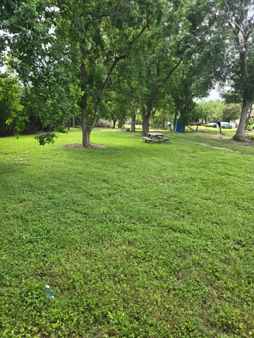 a view of grassy field with benches and trees all around