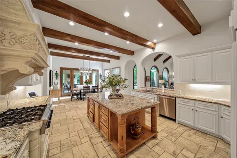 a kitchen with stainless steel appliances granite countertop a stove a sink dishwasher and chairs with wooden cabinets