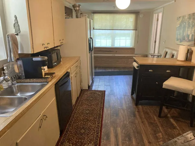 a kitchen with a sink stove and wooden floor