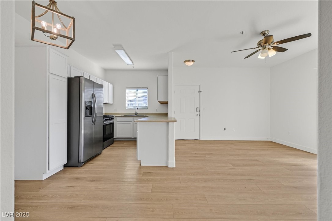 2291 West Horizon Ridge Parkway, Unit 1206 Henderson, NV 89052 - Photo 28 of 29 Kitchen featuring stainless steel fridge with ice dispenser, light countertops, open floor plan, white cabinets, and light wood-style flooring