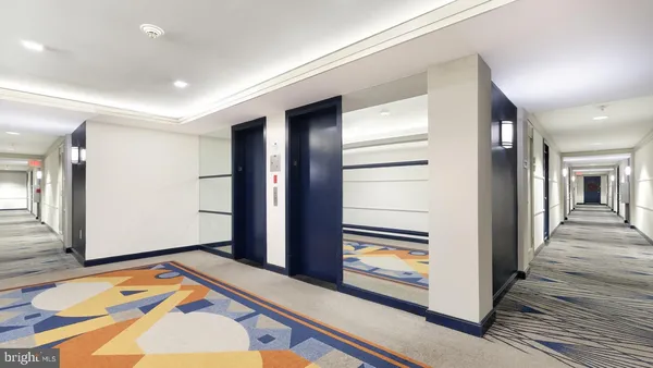 a view of a hallway to a livingroom with wooden floor and windows