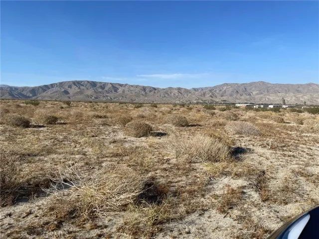 a view of a dry yard with mountains in the background