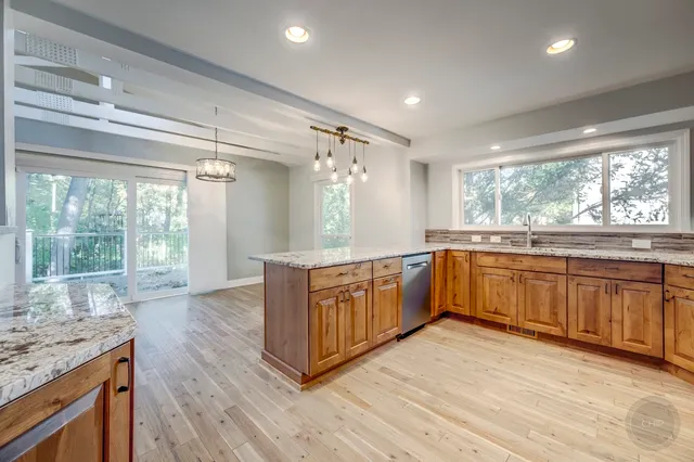 a view of an empty room with wooden floor and a ceiling fan
