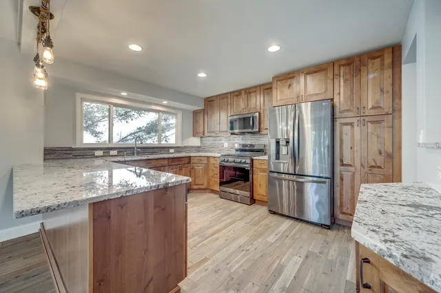 a kitchen with kitchen island granite countertop a sink a stove a refrigerator cabinets and a counter top space
