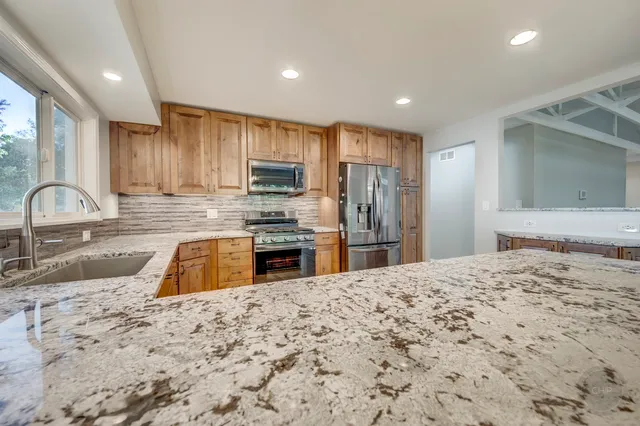 a kitchen with stainless steel appliances granite countertop a stove microwave and refrigerator