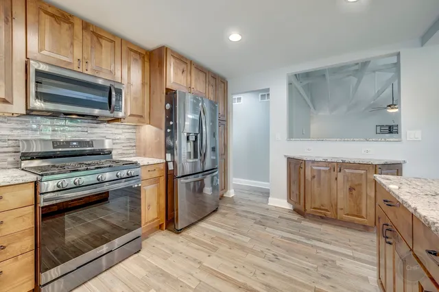 a kitchen with stainless steel appliances granite countertop wooden floors and white cabinets