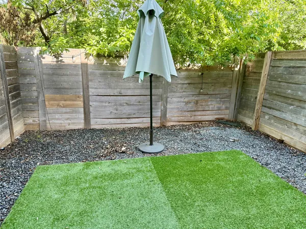 a view of a backyard with large trees and wooden fence