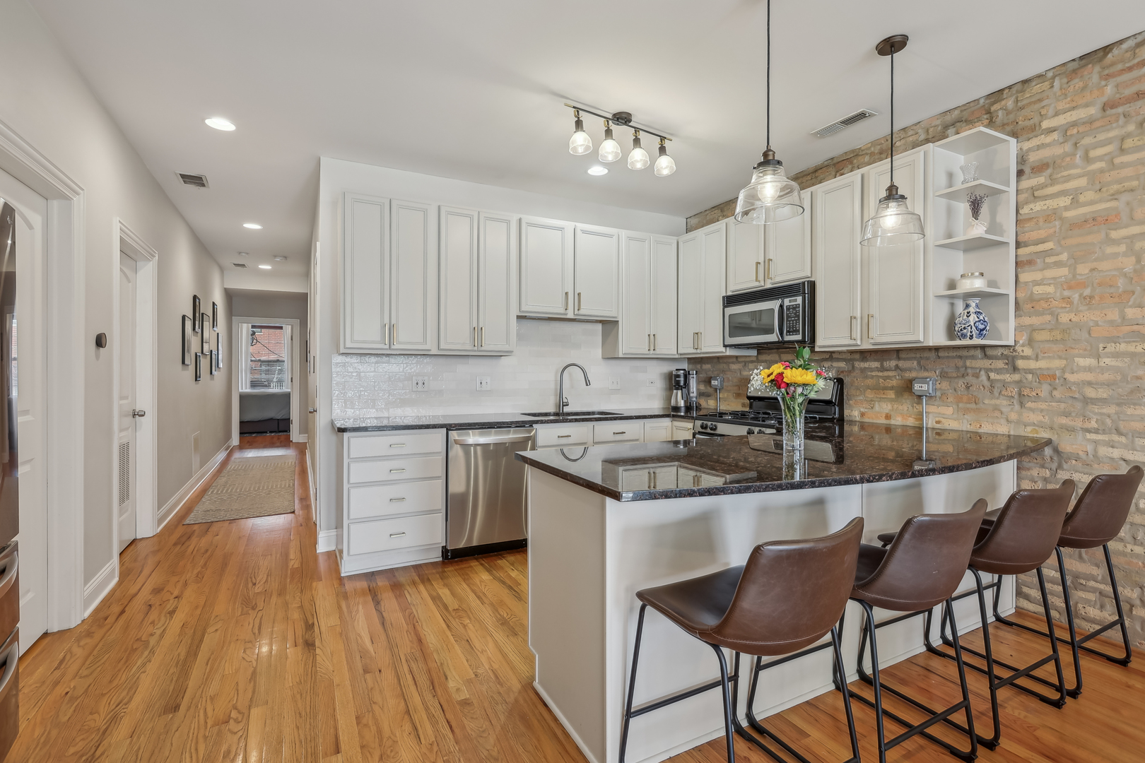 1025 West Madison Street, Unit 1 Chicago, IL 60607 - Photo 6 of 21 a kitchen with kitchen island granite countertop wooden floors and white cabinets