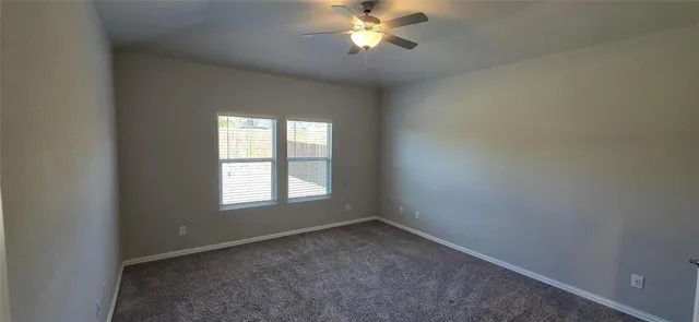an empty room with a window and a fan