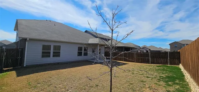 a view of a house with backyard and wooden fence