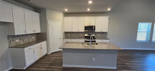 a kitchen with stainless steel appliances granite countertop a stove a sink and a microwave
