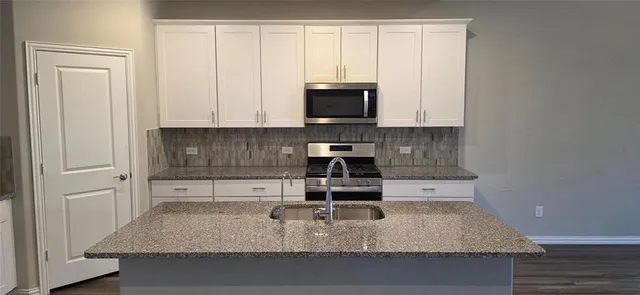 a kitchen with granite countertop a sink a stove and cabinets