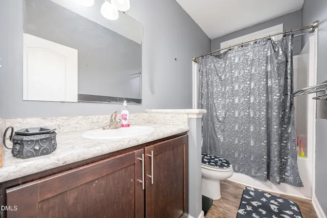 a bathroom with a granite countertop sink a toilet a shower and a mirror