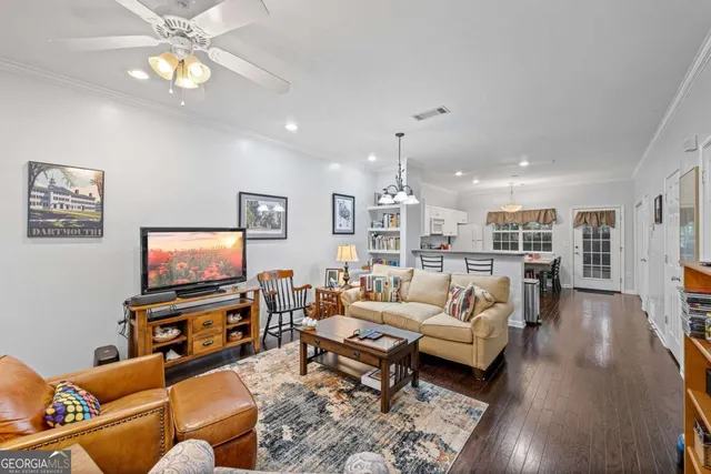 a living room with furniture kitchen view and a wooden floor
