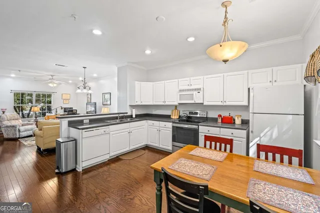 a kitchen with stainless steel appliances granite countertop a dining table chairs sink and white cabinets