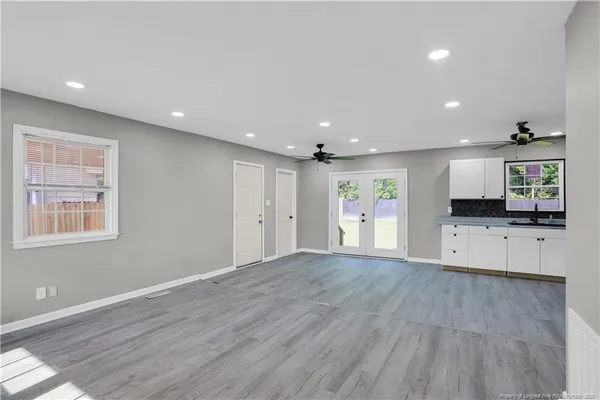 a view of an empty room with wooden floor and a kitchen