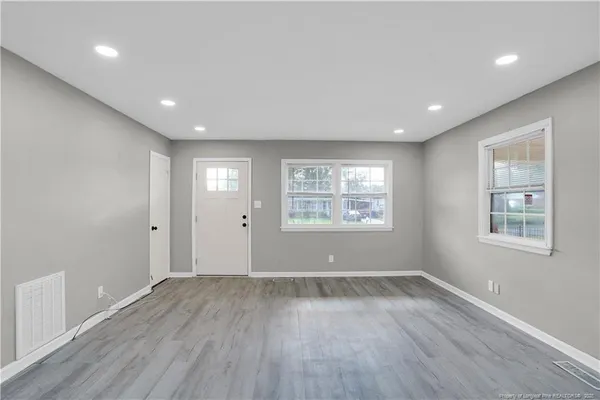 an empty room with wooden floor and windows