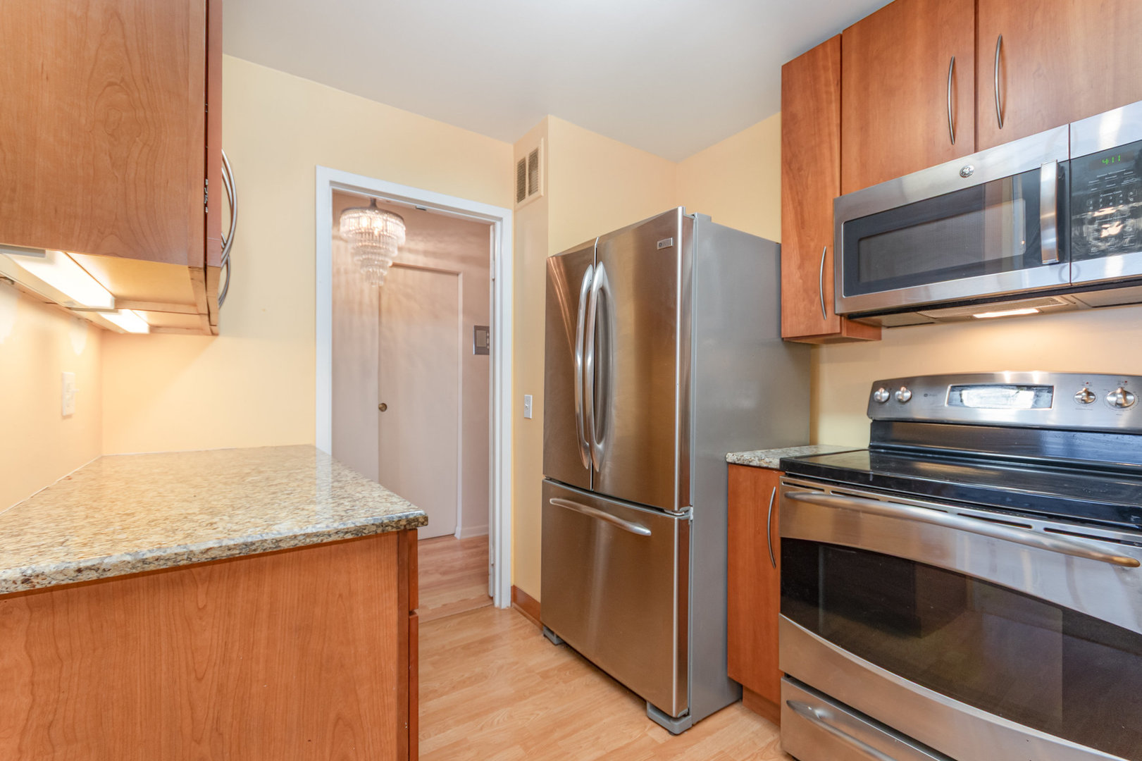5445 North Sheridan Road, Unit 2306 Chicago, IL 60640 - Photo 11 of 25 a kitchen with granite countertop a refrigerator stove and microwave