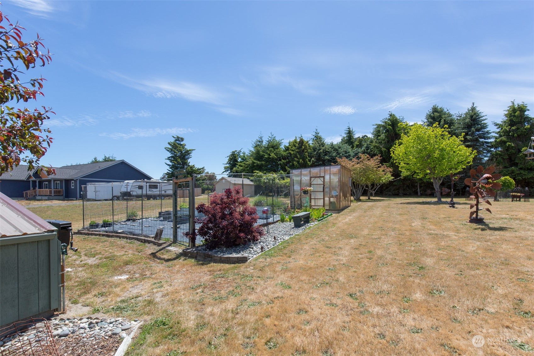 60 Klahhane Road Sequim, WA 98382 - Photo 23 of 36 a backyard of a house with table and chairs under an umbrella