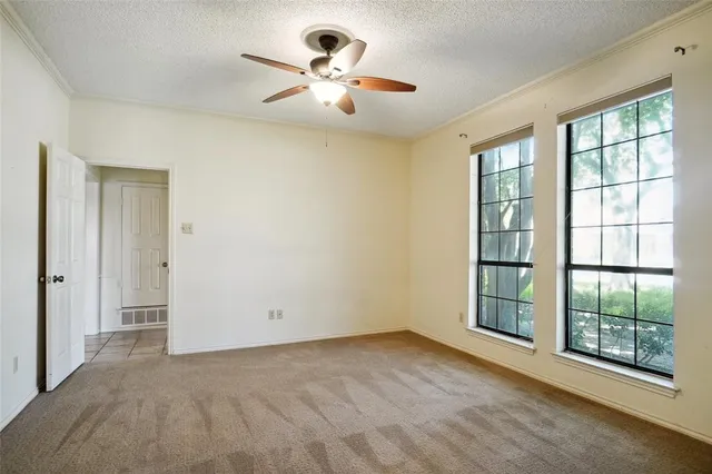 an empty room with windows and ceiling fan