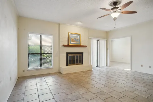 a view of an empty room with window and chandelier fan