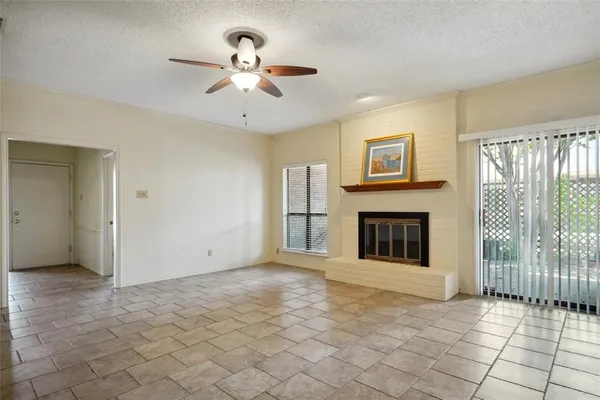 a view of a livingroom with a fireplace a ceiling fan and windows