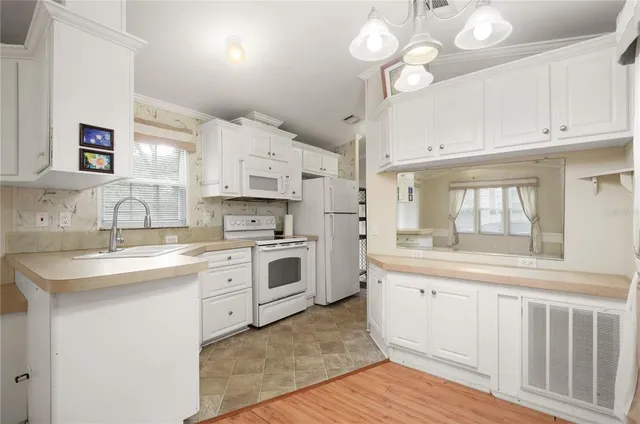 a kitchen with white cabinets stainless steel appliances and a chandelier