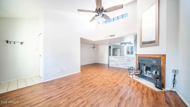 a view of a livingroom with a fireplace a ceiling fan and wooden floor