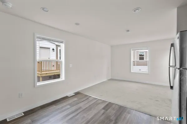 a view of an empty room with a window and wooden floor
