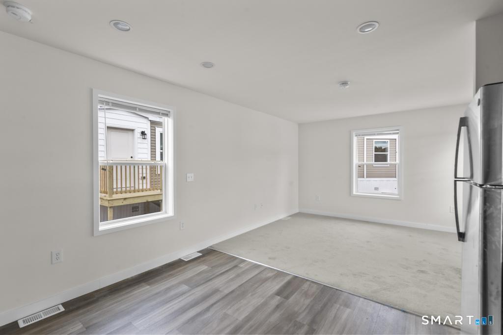 55 Sugar Street, Unit 14 Newtown, CT 06470 - Photo 6 of 18 a view of an empty room with a window and wooden floor