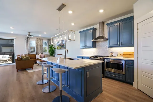 a kitchen with a stove a sink dishwasher a refrigerator and a dining table with wooden floor