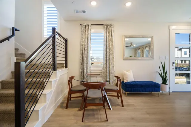 a kitchen with a stove a sink dishwasher a refrigerator and a dining table with wooden floor