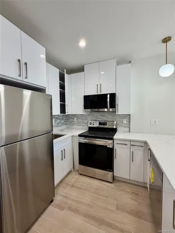 a kitchen with white cabinets stainless steel appliances and a refrigerator