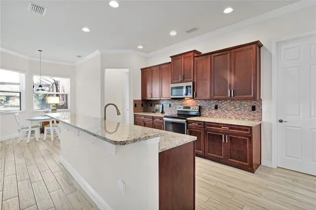 a kitchen with stainless steel appliances granite countertop a stove top oven a sink dishwasher and a refrigerator with wooden floor