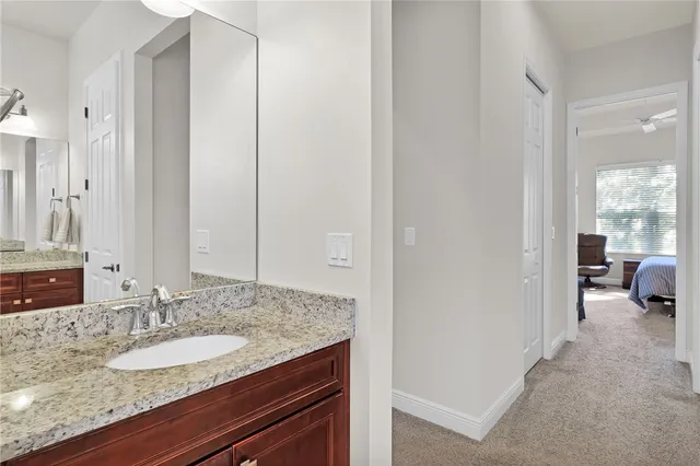 a en suite bathroom with a granite countertop sink and a mirror