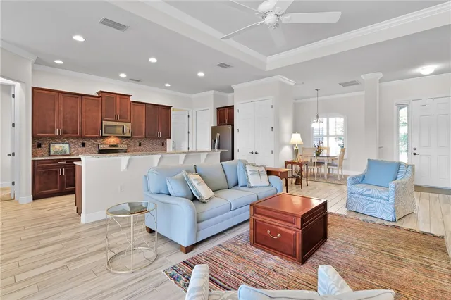a living room with stainless steel appliances furniture a rug and a kitchen view